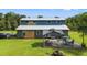 Exterior view of the home with a metal roof, outdoor seating area, and a spacious yard at 11151 Lu Wista Ln, Brooksville, FL 34601