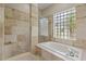 Bathroom featuring tub, separate shower, glass block window, and designer tile throughout at 1212 Halifax Ct, Tarpon Springs, FL 34688