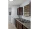 Kitchen with a stainless steel sink, granite countertop, brown cabinetry, and a window view to the yard at 13289 Joy Path, Brooksville, FL 34601
