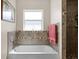 Bathroom featuring a soaking tub with stone surround, bright window, and a towel rack at 13419 Banner Rd, Spring Hill, FL 34609