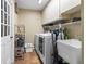 Bright laundry room with modern washer and dryer, sink, and storage shelves at 13419 Banner Rd, Spring Hill, FL 34609