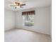 Simple bedroom with neutral carpet, large window with blinds, and a ceiling fan at 18325 Whitacre Cir, Hudson, FL 34667