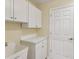 Well-lit laundry room with storage cabinets and a utility sink at 18325 Whitacre Cir, Hudson, FL 34667