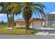 Charming tan home featuring an attached garage and a well-maintained front yard with mature palm trees at 3403 Holly Springs Dr, Hernando Beach, FL 34607