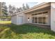 Spacious backyard with a brick patio, lawn, and sliding glass doors leading into the home at 4412 Caliquen Dr, Brooksville, FL 34604