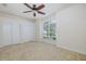 Bedroom with a ceiling fan, carpeted floor, large window, and double door closet at 4412 Caliquen Dr, Brooksville, FL 34604