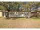 Exterior view of a home featuring mature trees, a lush lawn, and rear windows at 4412 Caliquen Dr, Brooksville, FL 34604