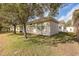 Exterior view of the rear of the home featuring mature trees and a lush lawn at 4412 Caliquen Dr, Brooksville, FL 34604