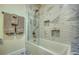 Close up on marble tiled shower with built-in mosaic shelves and modern fixtures at 6613 Josie Ln, Hudson, FL 34667