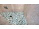 Close-up of mosaic tile shower floor with a modern drain and contrasting gray wall tiles at 6613 Josie Ln, Hudson, FL 34667
