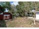 Backyard view with mature trees, utility shed, and concrete picnic table, offering ample space for outdoor activities at 686 Manor W Dr, Dunedin, FL 34698
