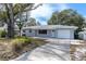 Charming single story home featuring mature trees, a front yard, and a one car garage at 686 Manor W Dr, Dunedin, FL 34698