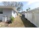 Side yard view of a home with fencing, gate and mature landscaping at 686 Manor W Dr, Dunedin, FL 34698