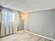 Bedroom featuring gray walls, laminate flooring, a window with white curtains and a lamp at 7109 Kirsch Ct # 2, New Port Richey, FL 34653
