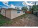 Exterior rear view of home with tan stucco, wooden privacy fence and minimal vegetation at 8715 Robilina Rd, Port Richey, FL 34668