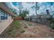 Home featuring a backyard with a wooden fence, vegetation, and tan stucco siding at 8715 Robilina Rd, Port Richey, FL 34668
