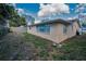 Home back exterior view, showcasing stucco siding and foliage at 8715 Robilina Rd, Port Richey, FL 34668