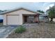 Home exterior showcasing tan stucco, brick, front porch with chairs and a single car garage at 8715 Robilina Rd, Port Richey, FL 34668
