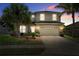 Two-story home featuring a two-car garage, landscaped yard, and mature palm trees against a colorful sunset sky at 8788 Fetterbush Ct, Brooksville, FL 34613