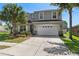 Home featuring a wide driveway, lush tropical landscaping, and classic architectural details on a sunny day at 8788 Fetterbush Ct, Brooksville, FL 34613
