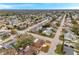 Wide aerial view of a neighborhood with an in-ground pool, mature trees, and adjacent streets at 9220 Saint Regis Ln, Port Richey, FL 34668