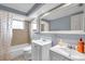 Bright bathroom featuring double sink vanity, neutral tile, and shower over tub at 9220 Saint Regis Ln, Port Richey, FL 34668