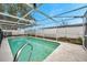 Backyard view of an in-ground pool surrounded by an awning and fencing at 9220 Saint Regis Ln, Port Richey, FL 34668