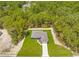 Aerial view of a home nestled in a forest, featuring a well-kept lawn and long driveway at 11345 Thrasher Ave, Weeki Wachee, FL 34614