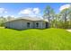 Exterior view of the home highlighting the green lawn, siding, and backyard at 11345 Thrasher Ave, Weeki Wachee, FL 34614
