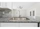 The kitchen features stainless steel sink, gray tile backsplash and granite counters at 11345 Thrasher Ave, Weeki Wachee, FL 34614