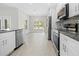 Bright modern kitchen featuring stainless steel appliances, white cabinets, and wood-look tile floors at 11345 Thrasher Ave, Weeki Wachee, FL 34614