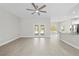 Bright living room features wood-look tile flooring, ceiling fan, and doors leading outside at 11345 Thrasher Ave, Weeki Wachee, FL 34614