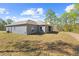 Rear view of a gray house with a spacious yard surrounded by trees at 11345 Thrasher Ave, Weeki Wachee, FL 34614