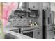 Kitchen with stainless steel appliances, gray cabinets, and modern backsplash at 12706 N Ola Ave, Tampa, FL 33612