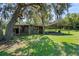 Rustic barn and stables with metal roof and fenced area surrounded by a vast grassy field at 12757 Circle Lake Dr, Hudson, FL 34669