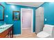 Bright bathroom featuring a sleek toilet, vanity with wood cabinets, and turquoise walls at 12757 Circle Lake Dr, Hudson, FL 34669