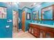 Beautiful bathroom with wood cabinets, dual sinks, glass enclosed shower and turquoise walls at 12757 Circle Lake Dr, Hudson, FL 34669