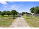Exterior view of home, with a long driveway, mature trees and front fence at 12757 Circle Lake Dr, Hudson, FL 34669