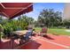 Charming outdoor patio with a dining set, colorful flowers, and a view of the grassy lawn and barn in the backyard at 12757 Circle Lake Dr, Hudson, FL 34669