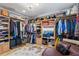 Spacious walk-in closet with hardwood floors, custom storage, clothing racks, shelves, and a comfortable leather couch at 12757 Circle Lake Dr, Hudson, FL 34669
