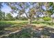 Sprawling yard with mature trees, distant buildings, and partly shaded areas in a rural area at 12757 Circle Lake Dr, Hudson, FL 34669