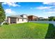 Spacious backyard featuring green lawn, screened lanai, privacy fence, and view of neighboring pool at 1801 Loch Haven Ct, Trinity, FL 34655