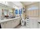 Well-lit bathroom with double sinks, vanity, and a soaking tub under an arched window at 18515 Gentle Breeze Ct, Hudson, FL 34667