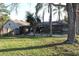 Back exterior view of home with screened-in patio and pool, surrounded by mature trees at 2233 Egret Walk Ct, New Port Richey, FL 34655
