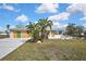 Home exterior featuring a lawn with tropical landscaping and a boarded-up garage at 3449 Companero Entra, Hernando Beach, FL 34607