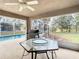 View of a screened-in lanai with grill, table, ceiling fan and view of the pool area at 469 Fairbanks Rd, Spring Hill, FL 34608