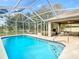 View of the sparkling in-ground pool with a screened-in enclosure and covered lanai at 469 Fairbanks Rd, Spring Hill, FL 34608