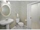 Charming powder room features a pedestal sink and toilet set against a vintage wallpapered backdrop at 5050 Limestone Dr, Port Richey, FL 34668