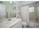 Cozy bathroom with a tub and shower, complemented by a pedestal sink, toilet, and mint-striped wallpaper at 5050 Limestone Dr, Port Richey, FL 34668
