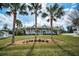 Inviting single-story home with a charming front porch framed by lush green lawn and mature palm trees at 5050 Limestone Dr, Port Richey, FL 34668